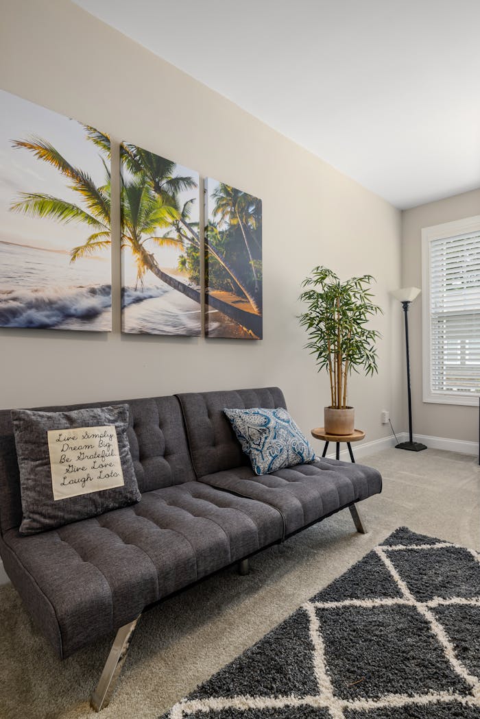 Contemporary living room interior featuring a grey sofa, abstract palm artwork, and houseplant.